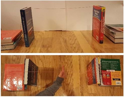 Two photographs: A side view shows two text books standing up vertically about 18 inches apart, with one long string tied around one book, strung across the gap and then tied around the second book. To the outer side of each standing textbook, a pile of three textbooks puts weight on the tail ends of the strings (anchorages). A view from above of the same setup shows a hand pressing down on the middle of the string across the gap between the two books, which does not result in the books falling inwards.