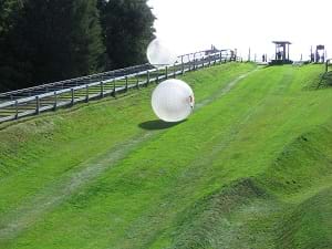 Zorbing, which shows a large ball rolling down a hill.