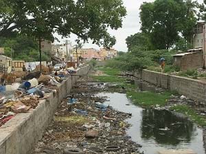 A polluted canal in India overflowing with garbage.
