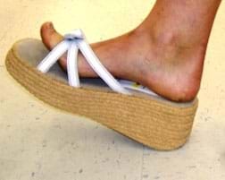 A photograph shows the bare foot of a person wearing a white-strapped sandal with a two-inch thick hemp platform sole.
