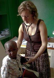 A female adult measures the heart rate of a child.