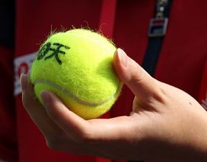 An individual holding a tennis ball in their hand.