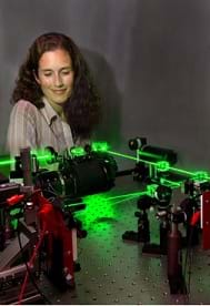 Photo shows a girl standing by green glowing laser beams.