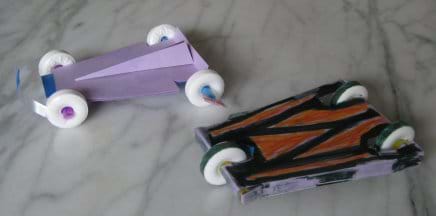 A photo shows two little race cars made from round white candies (for wheels), plastic drinking straws (for axles) and card stock (for cut and taped body chassis shapes).