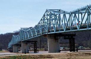 A photograph shows the Milton-Madison Bridge, a truss bridge that crosses a river in Indiana. The metal truss bridge is painted blue and rests on concrete piers.
