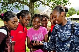 A US Navy officer shows five teenage girls a music video on her cellphone.
