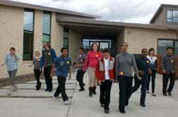 Photo shows nine high school students and two instructors walking out the front door of a building.