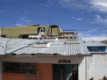 Photo shows a structure with a corregated silver-colored roof and three flat boxes on it. "Niño's" is written above the oopen front door.