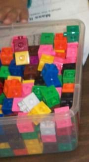 A photograph shows a clear plastic tub filled with assorted same-size snap cube blocks in many colors.