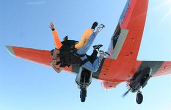 Two Skydivers jump out of an orange airplane.