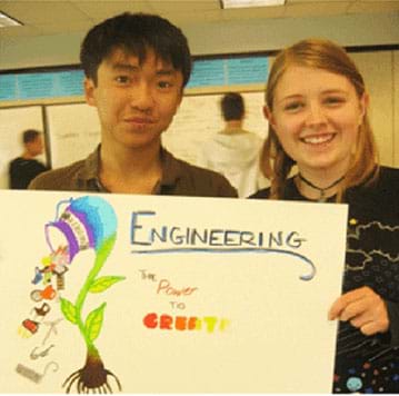Two teens hold a poster they made that says, "Engineering – the power to create." 