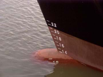 Photo shows a ship in water with numerical markings that indicate its displacement in the water.