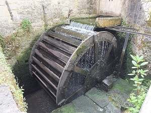 An overshot waterwheel showing water flowing through it in Goyet, Beligum.