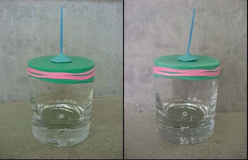 Two photographs both show a glass jar with a rubber band securing a piece of Mylar tight across the jar mouth and a toothpick stuck vertically into a piece of putty on top of the Mylar lid. In the left photo, the toothpick points straight up. In the right photo, the toothpick leans a bit to the right.