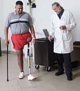 Photo shows a man testing his prosthetic leg as a doctor looks on.