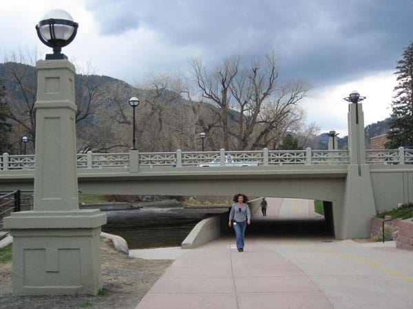A concrete beam bridge spans a river and a pedestrian path.