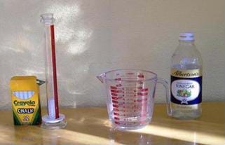 Photo shows a box of chalk, a graduated cylinder, a measuring glass and a bottle of vinegar.