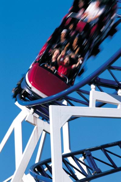 Photograph of people having fun riding on a speeding rollercoaster.