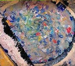 A photograph shows a big vat with hundreds of juice boxes soaking in water in an attempt to separate the paper, aluminum and plastic layers of the boxes.