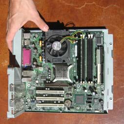 Photo shows complex arrangement of circuit boards, integrated circuits, pins, wires, chips and fan pulled from inside a PC.