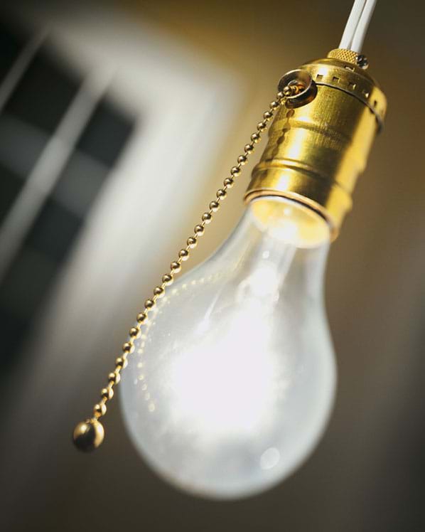 Photo shows a hanging bare light bulb with a pull cord.