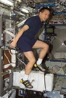 A photograph showing an astronaut ride an exercise bike while in outer space.