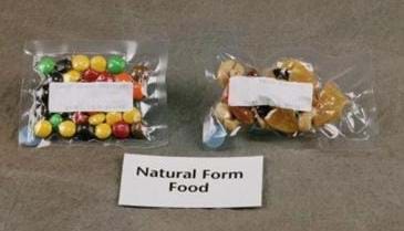 Photo shows colorful round candies, and trail mix encased in plastic. A nearby sign reads: "Natural Form Food."