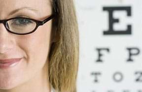 A photograph shows a young woman with glasses and a portion of an eye chart in the background.