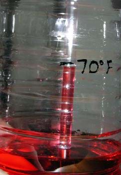 Photo shows a water bottle with red liquid in the bottom and a straw sticking in it. The red liquid has risen part way up the straw and where it ends is marked as 70°F.