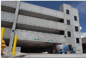 A photograph shows a four-story parking garage made of concrete. 