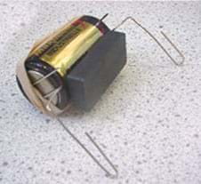 A photo shows the ceramic magnet on the side of the battery, along with the paperclips and rubber band. 