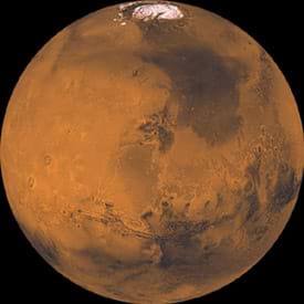 A round image of Mars shows its red surface and northern polar ice cap.