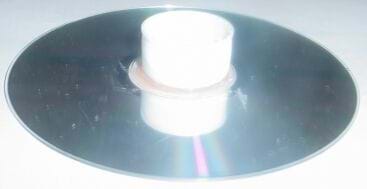 A photo shows a plastic bottle cap attached with the top of the lid glued to the middle of a round, silvery CD.