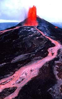 Photo of red lava spewing out of a volcano vent and flowing down its slope.
