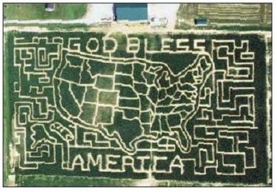 An aerial photograph of a corn field shows a map of the U.S., the words "God Bless America," and mazes on the outer edges of the field that have been cut into the field. The design was "mapped out" using inexpensive software, and then the farmer plowed the field accordingly using data loaded into a GPS receiver.