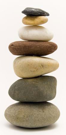 Photo shows a stack of seven various types of rounded rocks.