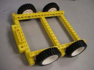 A photograph shows a LEGO chassis with four wheels on which the wooden block will be placed so that the vehicle can roll.