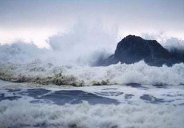 Image of waves crashing against a lone rock in the ocean.