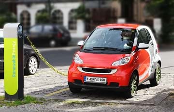 An electric car recharging its battery at a Renewable Energy charging post.