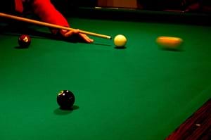 A pool table showing a white cue ball about to hit a pool ball.