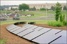 Two curved rows of solar panels on a tilted rack on the ground in a landscaped area.