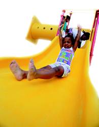 A photo of girl sliding down a playground slide.