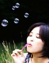 Photo shows a girl blowing bubbles using a plastic bubble wand.
