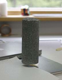 A photograph shows a two-inch square block of aerogel holding up a 4-kilogram cylinder of granite with no apparent deformation.