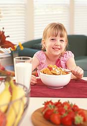 A photograph shows a girl at a table with a bowl of flaked cereal.