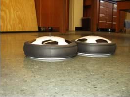 Photo shows side view of two hover pucks" on the floor.