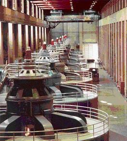 A row of seven gigantic cylindrical devices in a concrete room.