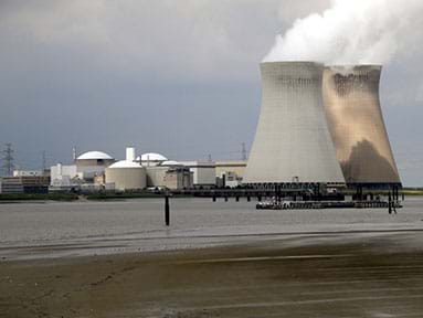 A photograph shows steam coming out of the tops of two Doel Nuclear Power Station cooling towers in Belgium.