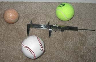 A photograph shows a marble sphere, tennis ball and baseball, plus a vernier caliper, which is a linear measuring instrument consisting of a scaled rule with a projecting arm at one end to which is attached a sliding vernier scale with a projecting arm that forms a jaw with the other projecting arm.