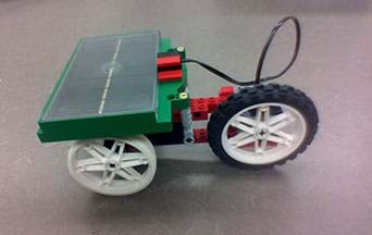 A photograph shows an example three-wheeled solar vehicle built with an eLAB LEGO Renewable Energy Set. A black solar panel is mounted on top, above the axle between two wheels.